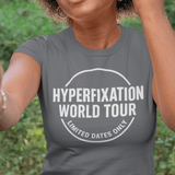 Person wearing a gray t-shirt with 'Hyperfixation World Tour' text outdoors.