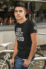 Man wearing a black t-shirt with 'Side Quest Legend' print, standing by a bicycle and urban background.