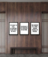 Three motivational wall art prints with empowering quotes displayed on a wooden wall.
