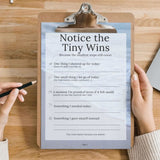 Notice the Tiny Wins worksheet on clipboard for mental wellness and self-reflection.