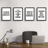 Four motivational wall art prints with empowering quotes for confidence and self-care in a modern office setting.