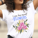 Woman wearing a white t-shirt with floral design and text, standing outdoors.