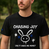 Man wearing a black t-shirt with a graphic design and text outdoors.