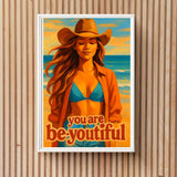 Framed artwork of a woman in a bikini with 'you are be-youtiful' text on a wooden wall.