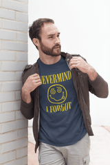 Man wearing a blue Unisex Heavy Cotton tee with the phrase 'NEVERMIND I FORGOT' and a quirky smiley graphic.
