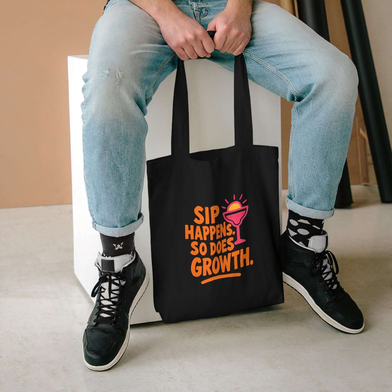 Sip Happens Growth Tote Bag displayed on a person, showcasing its vibrant design and eco-friendly appeal.