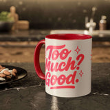 Colorful coffee mug with a bold design saying 'Too Much? Good.' on a kitchen countertop.