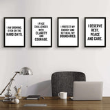 Four motivational wall art prints with empowering quotes for confidence and self-care in a modern office setting.
