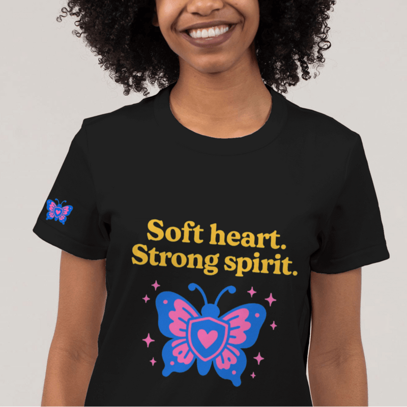 Person wearing a black t-shirt with colorful graphics and text on a plain background
