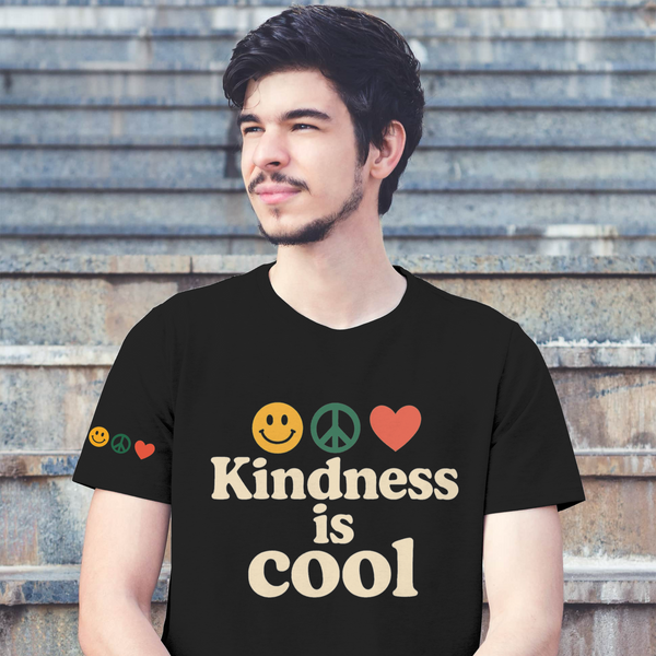 Person wearing a black t-shirt with 'Kindness is Cool' text and emojis, sitting on steps.
