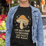 Person wearing a black t-shirt with a mushroom graphic and text, standing outdoors.