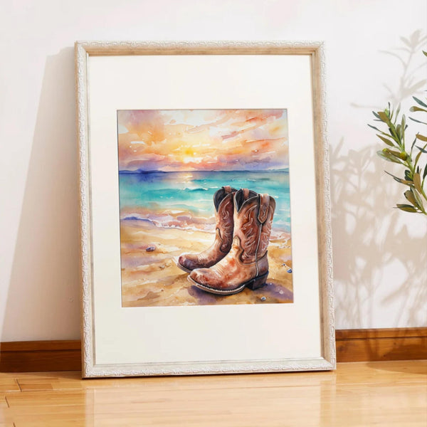 Framed artwork of cowboy boots on a beach with a sunset.