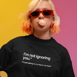 Person wearing a black t-shirt with text, blowing a bubble, against a colorful background