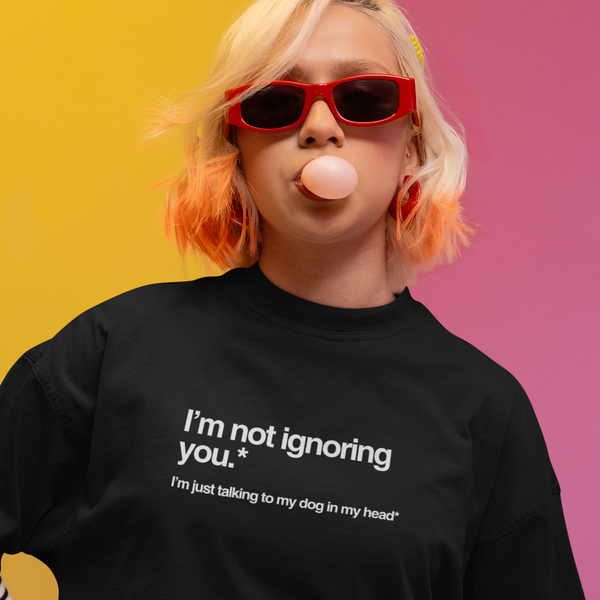 Person wearing a black t-shirt with text, blowing a bubble, against a colorful background