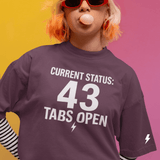Person wearing a purple t-shirt with 'CURRENT STATUS: 43 Tabs Open' text, standing against a multicolored background.